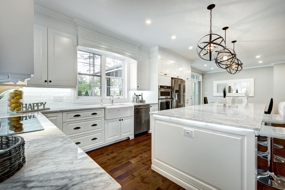 A bright white kitchen with marble counters, freshly cleaned