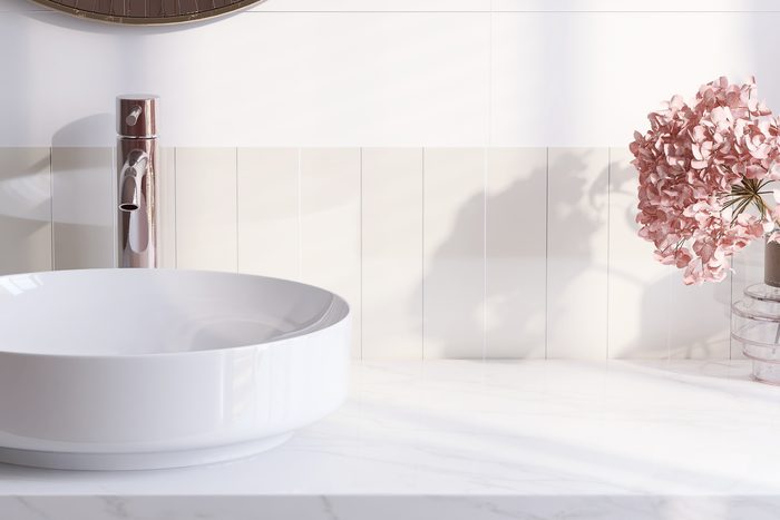 A clean white bathroom vanity with a vessel sink and fresh flowers