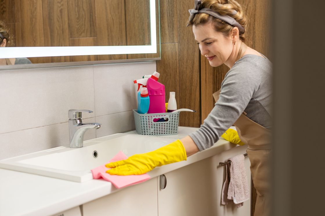 A Heron cleaner wiping down a bathroom vanity