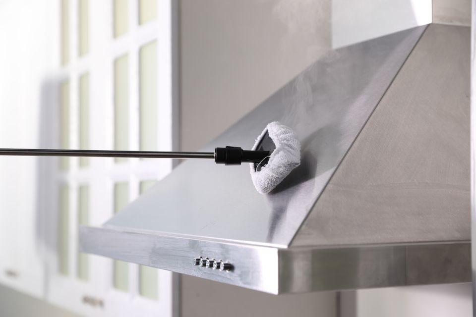 A steam cleaner lifting grease from a stainless range hood