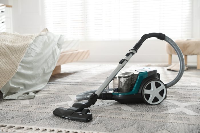 A vacuum cleaner on a rug in a bright, tidy bedroom