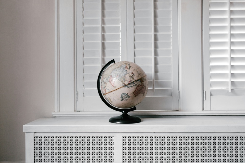 White interior window shutters with horizontal louvres behind a globe on the sill