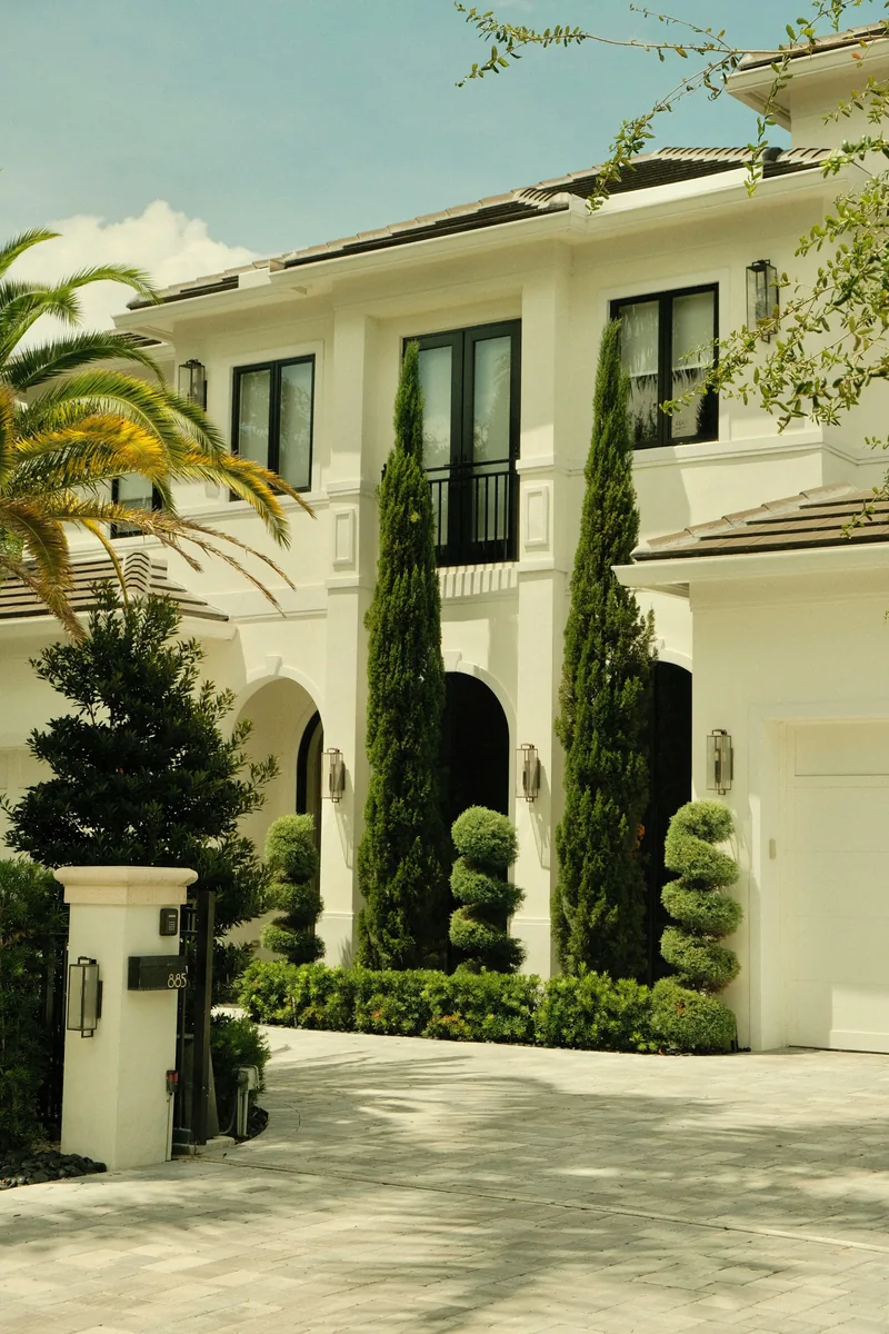 White home with tall windows and a landscaped entrance
