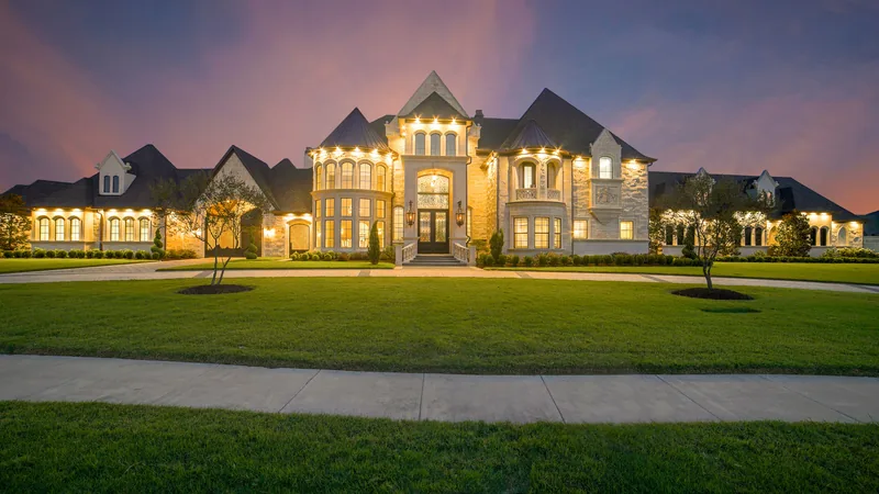 Large stone home with an illuminated entrance at dusk