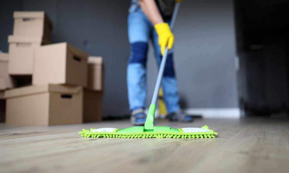 Mopping the floor of an empty home with packing boxes stacked behind