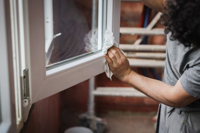 A worker cleaning a newly installed window frame on a build site